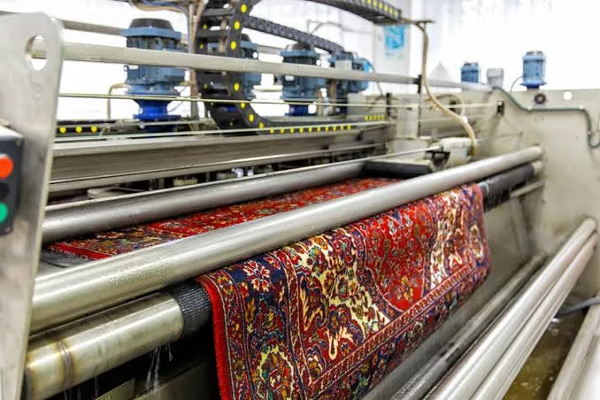 Oriental rug passing through a professional rug washing and rinsing line